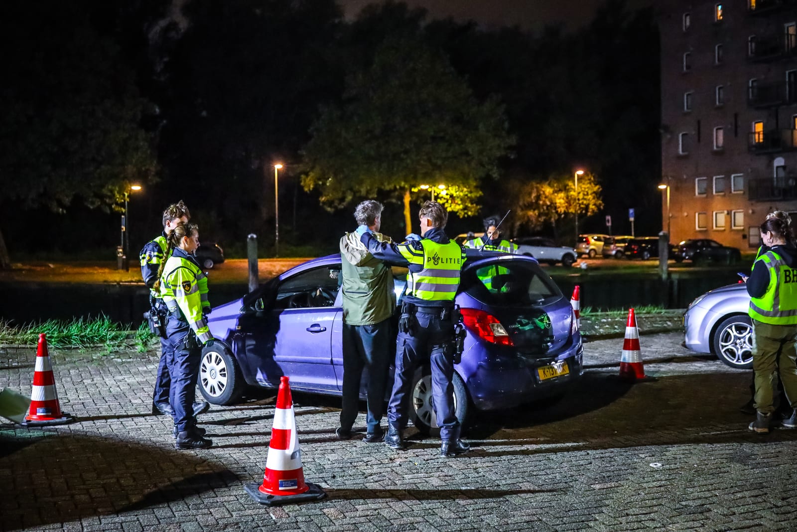 Agenten controleren een automobilist tijdens de grootschalige controle in de Vlaardingse Oostwijk.